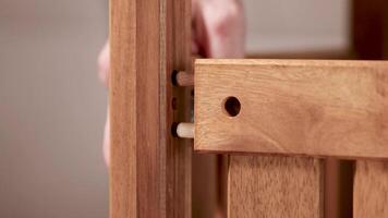 Hands assembling wooden furniture using dowels in a softly lit environment. Close-up view highlights precision and craftsmanship video