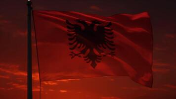 Albanian flag waving on a flagpole with orange sky video