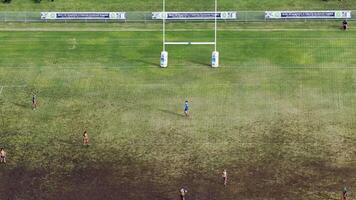 Children engage in a rugby match on a muddy field under bright daylight, captured from an aerial perspective in Gold Coast, Australia video