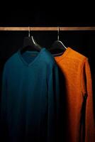 Plain Orange And Teal Sweatshirts on Hanger, Isolated on Black Background photo