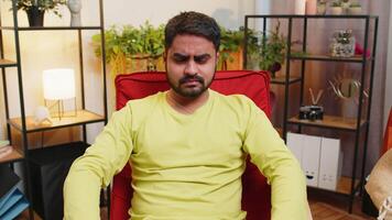 Hey you. Strict unhappy Indian man pointing hand finger to camera, looking angry, making choice, choosing guilty, noticing suspicious, accusing for mistake at home room apartment. Guy sits on chair video