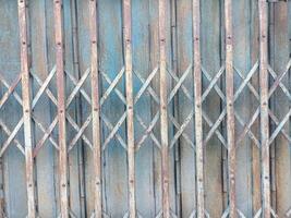 Rusty metal gate with crisscross pattern and weathered blue paint, showing signs of age and exposure to elements, creating textured and industrial appearance photo