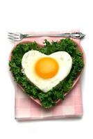 A heart shaped egg in a plate with a fork photo