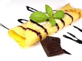 A chocolate crepe with a chocolate sauce and a piece of basil photo