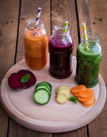 A wooden table with four jars of juice on it photo