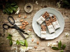 Granola bars and almonds on a plate on a wooden table photo