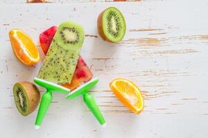 A bunch of fruit and a popsicle on a white table photo