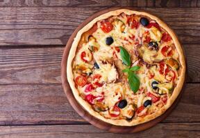 A pizza on a wooden table with a green leaf photo