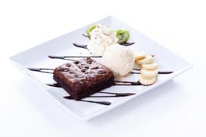 A square plate with a piece of cake, ice cream, and bananas photo