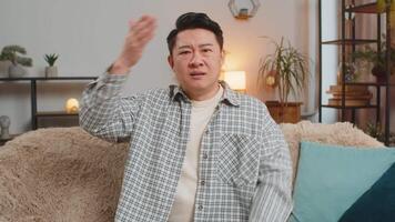 Face palm. Shame on you. Upset man making disrespect gesture, feeling bored disappointed in fail results bad news. Portrait of Middle Eastern guy in home living room sitting on couch sofa. Lifestyles. video