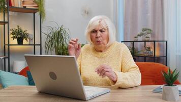 Displeased senior woman use laptop notebook typing browsing working, loses becoming surprised sudden lottery results bad news fortune loss game fail computer virus. Elderly mature grandmother at home video