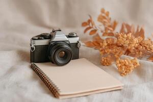 Vintage Camera and Notebook Still Life Photography Autumnal Hues and Dried Flowers. A nostalgic scene capturing the essence of analog photography and autumn's warm tones. photo