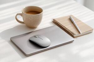 Laptop, Mouse, Coffee, and Notebook on a Desk A Minimalist Workspace Setup for Productivity photo
