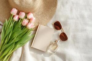 Springtime Relaxation Tulips, Sun, and Style. A beautiful flatlay featuring pink tulips, a straw hat, sunglasses, perfume, and a b photo