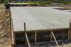 New concrete stretches across the site, framed by wood, showing progress in the building process during the day photo