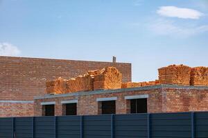 Workers are preparing a building structure with numerous bricks neatly piled on top of a partially completed wall photo