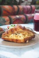 Delicious croissant sandwich with eggs and drink on table photo