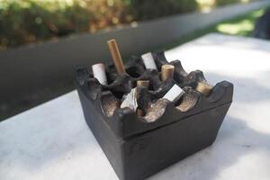 Ashtray filled with cigarette butts on an outdoor table photo
