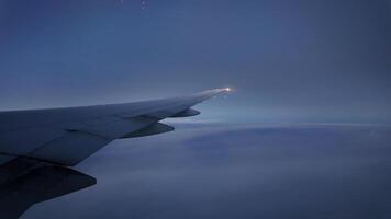 Wing of an aircraft gliding through twilight clouds photo