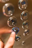 Unrecognizable person selecting the L by pressing one of the elevator buttons with his or her finger photo