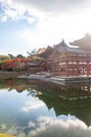 Byodo-in Temple Uji Kyoto Japan, Traditional temple reflected in serene water under a cloudy sky. photo