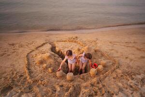 Siblings build an elaborate sandcastle on a sunny beach afternoon photo