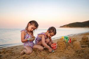 Siblings building sandcastles at sunset on a tranquil beach photo