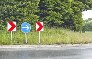 At a roundabout in Denmark, the signs show a red and white arrow and a white arrow in Blue sign photo