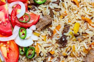 a plate of rice and meat with tomatoes and peppers photo