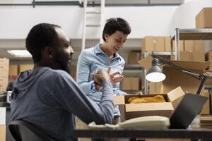 Multiethnic staff overseeing daily tasks in a depot distribution hub, using online logistics tools to track merchandise and streamline order fulfillment in a small scale industrial setting. photo