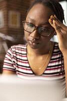 Female entrepreneur experiences headache while seated at home office desk, trying to manage multiple projects. Close up of fatigued woman massaging her temples, struggling to focus on laptop. photo