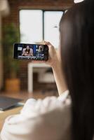 Female manager using cellphone to communicate with remote colleagues. Self employed woman seated at home with digital device, contributing to professional conversation remotely. photo
