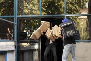 Takeaway courier drops multiple pizza boxes while approaching front door. The meal order spills across the sidewalk as a client looks on, dissatisfied with the clumsy and careless food service. photo