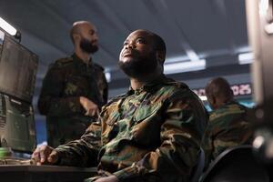 Air defense command specialist using radar equipment to detect incoming ballistic missiles. African american army soldier in base of operations scanning rockets approaching borders, deploying shields photo