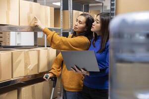 Asian staff member using crutches while she processes shipments in a logistics center. Small business supports reduced mobility through inclusive workspace, supportive storage environment. photo