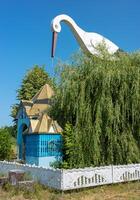 Chapel in teresva with stork sculpture and flourishing willows on a clear day photo