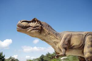 Artificial dinosaur tyrannosaurus, close-up of dinosaur head against sky background photo