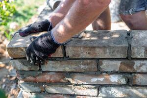 Bricks being laid on a partially built brick structure with mortar. Construction of a barbecue. photo