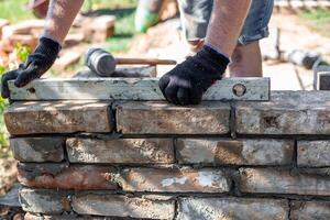 Close-up of leveling bricks during construction of brick structure using spirit level. photo
