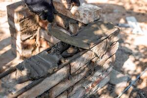 man applying mortar to brick structure with trowel, preparing for further construction. photo