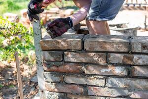 a builder using a level to ensure the alignment and stability of a brick wall during construction photo