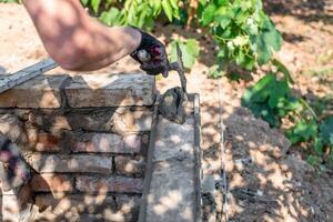 man applying mortar to brick structure with trowel, preparing further construction. photo