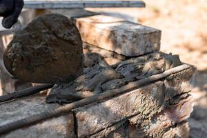 man applying mortar to brick structure with trowel, preparing for further construction photo