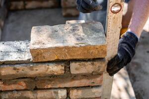 Closeup of leveling bricks during construction of brick structure using spirit level. photo