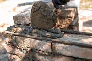 applying wet cement to brick structure showing texture and process of barbecue construction, close-up.. photo