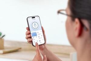 Woman using smartphone smart home app with door lock and device management functions photo