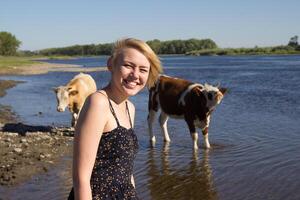 Girl Smiling by a River With Cows During a Sunny Day in a Rural Area photo