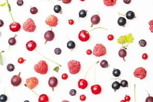 Assortment of fresh summer berries including red cherry, raspberry, gooseberry, blackcurrant scattered on white. photo
