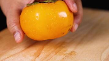Hands preparing to peel a ripe persimmon video