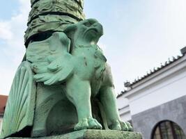 Green mythical creature sculpture with wings on outdoor post photo
